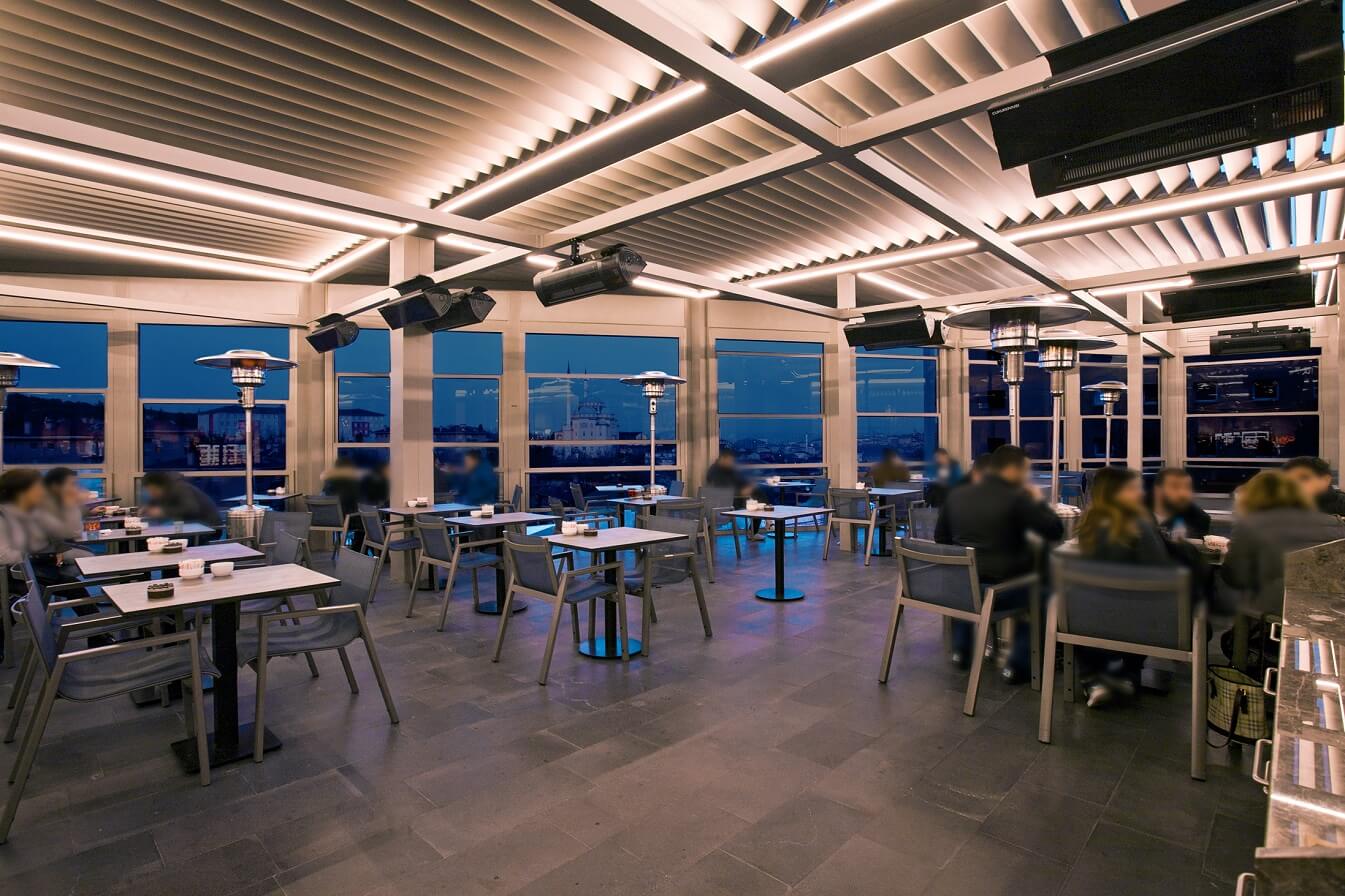 A heated restaurant with an illuminated rotating louvered roof pergola