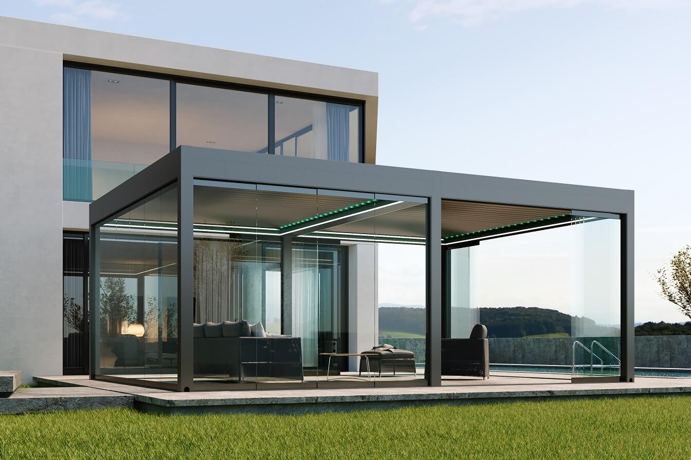 A charcoal grey pergola with frameless glass sliding doors protecting an outdoor room next to a pool