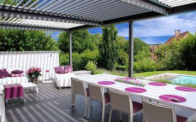 A gray louvered roof pergola over tables and chairs