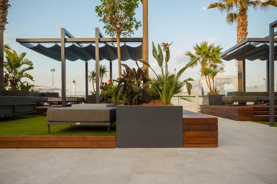 Grey Ancona pergola on a platform with artificial turf and greenery