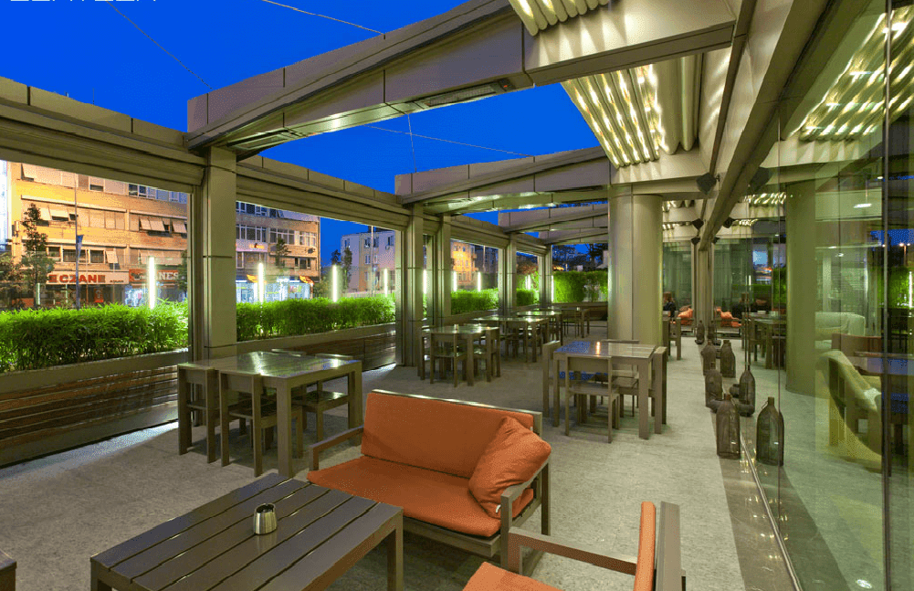 Ivory retractable roof pergolas with lights covering grey furniture