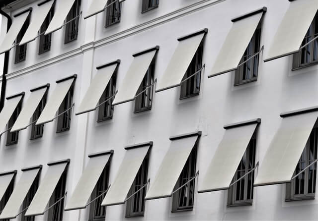 Rows of manual retractable window awnings  on an apartment building