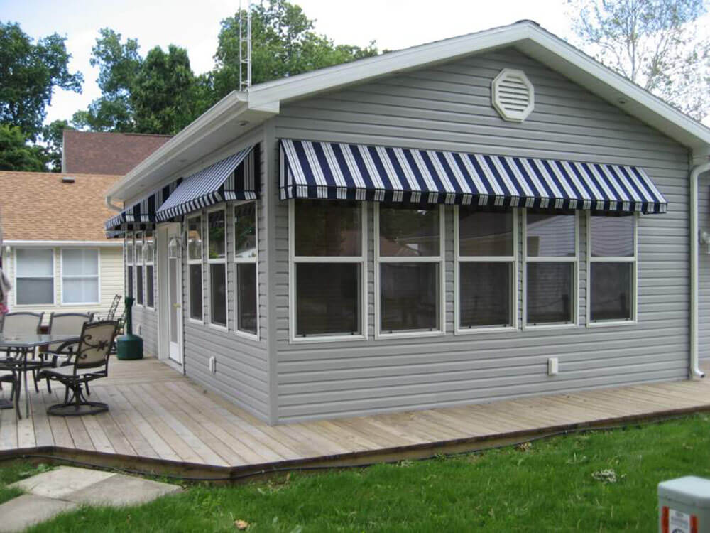 Striped awnings give life to a gray house